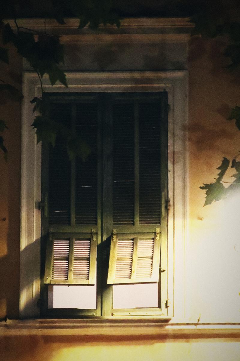 Fenêtre aux volets verts baignée de lumière dorée