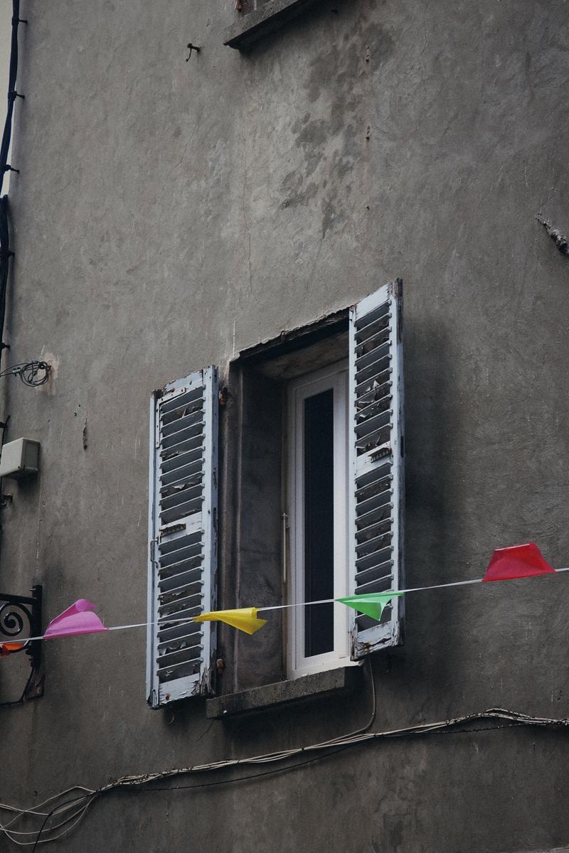Volets blancs et guirlande de fanions sur une façade grise