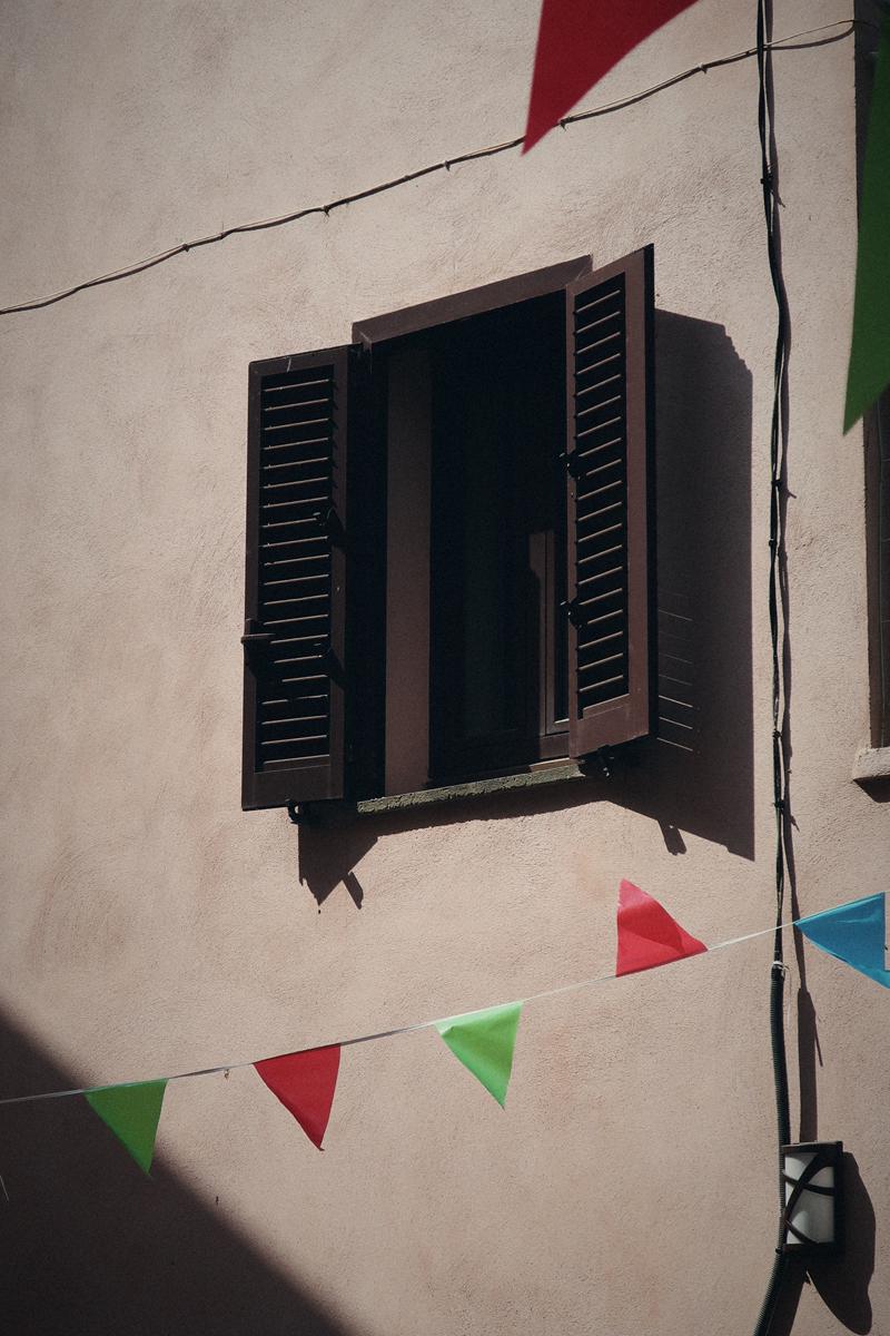 Volets entrouverts et fanions sur une façade claire